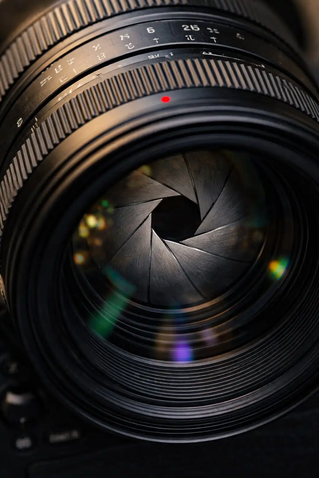 Detail objektívu fotoaparátu s viditeľnou clonou a rôznymi hodnotami f čísla