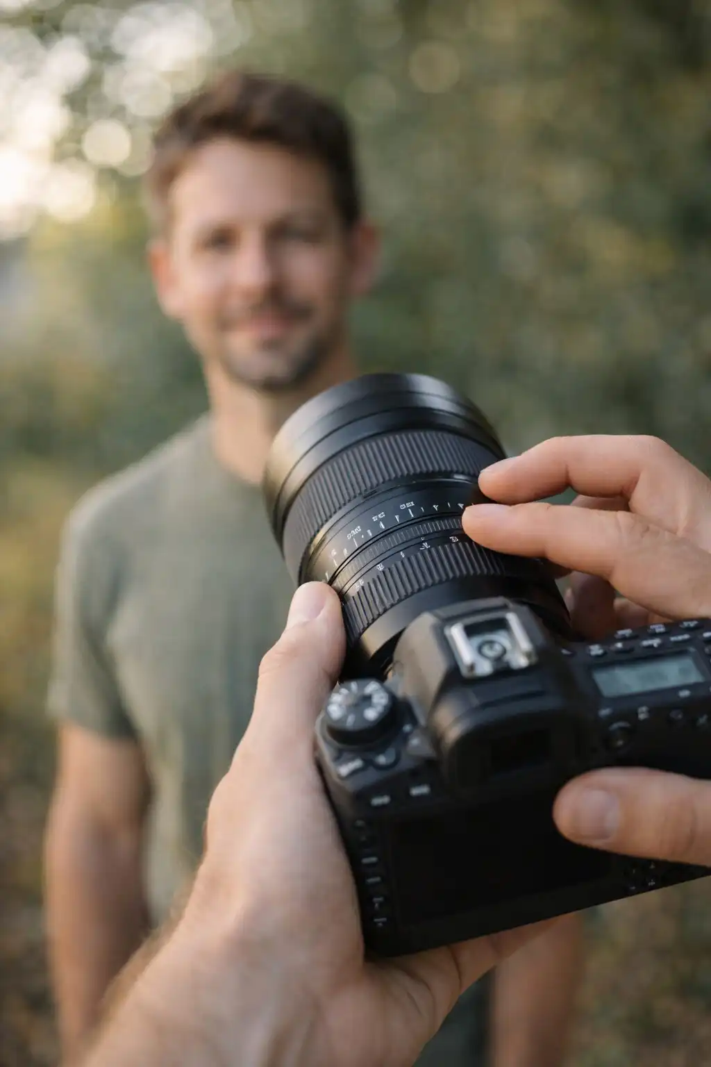 Fotograf drží fotoaparát a nastavuje clonu objektívu pri portrétnom fotografovaní v prirodzenom svetle