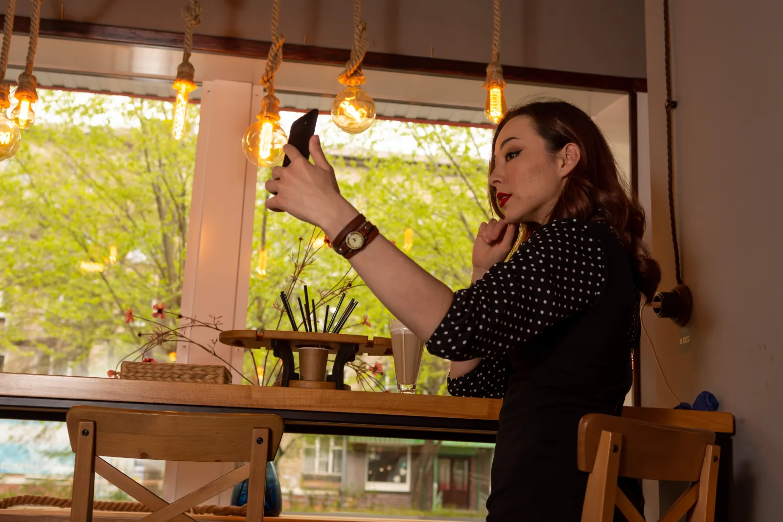 Žena drží smartfón pri fotografovaní v interiéri kaviarne