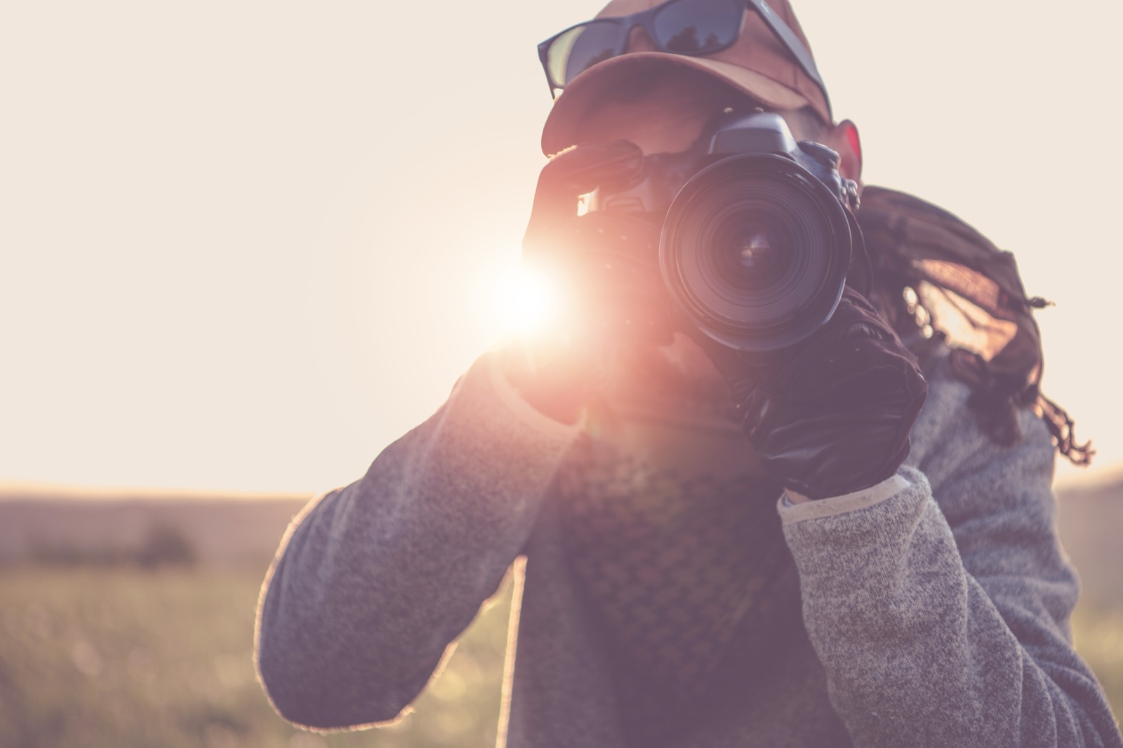 Fotograf s fotoaparátom pri oku v protisvetle