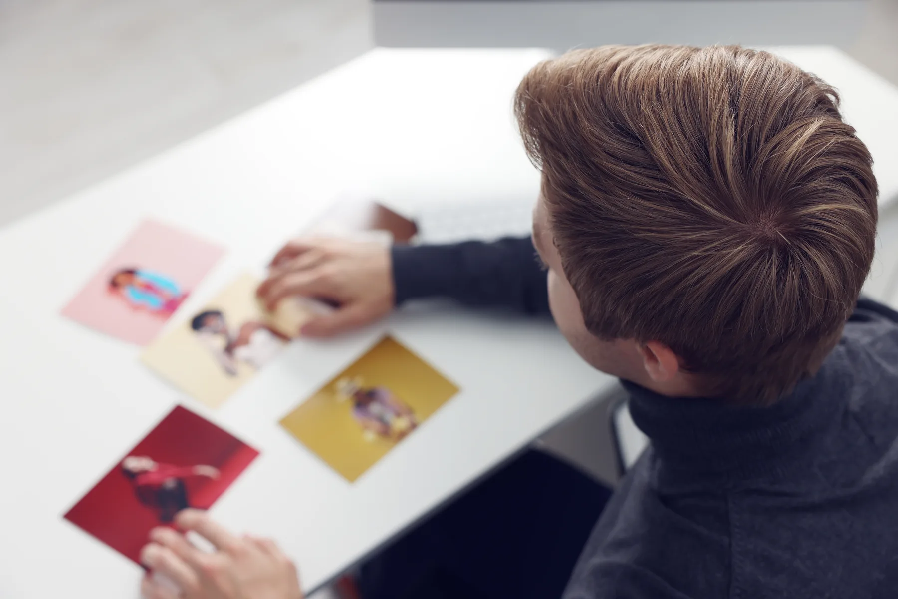 Muž kontroluje farebné fotografie vytlačené na stole