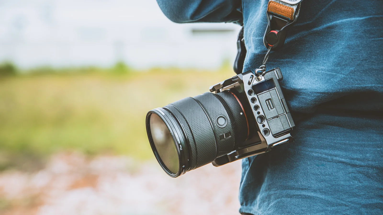 Ilustračná fotografia bezzrkadlového fotoaparátu na ramene fotografa