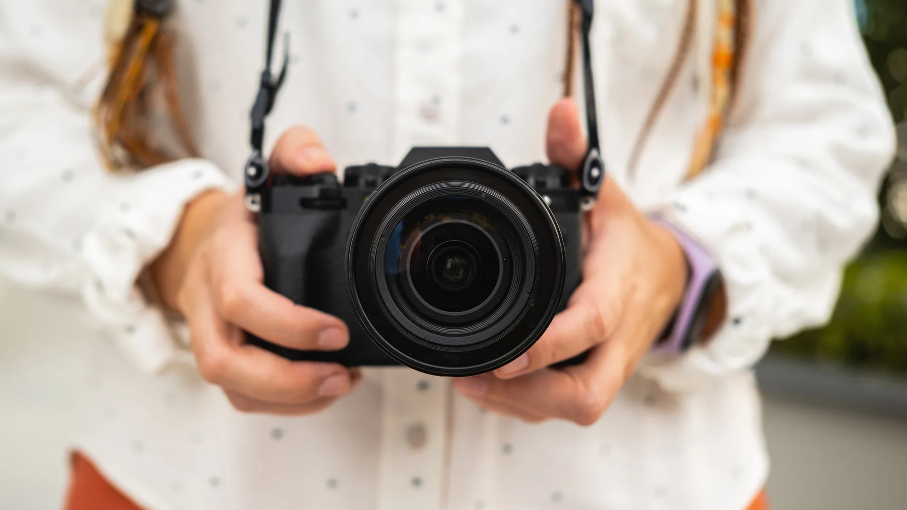 Začiatočníčka drží fotoaparát pri praktickom fotografovaní v exteriéri