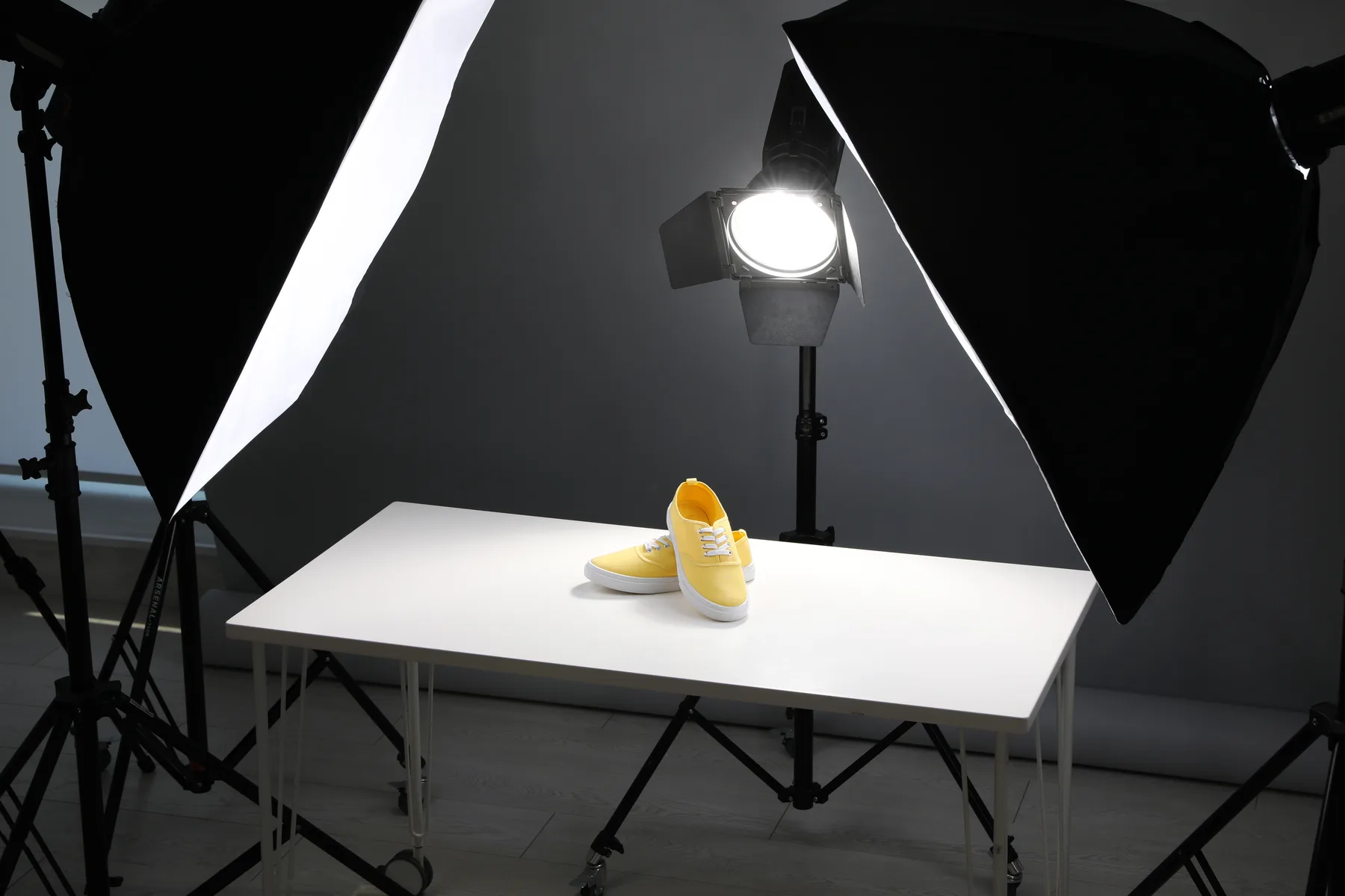 Žlté tenisky na bielom stole osvetlené softboxmi pri produktovom fotení