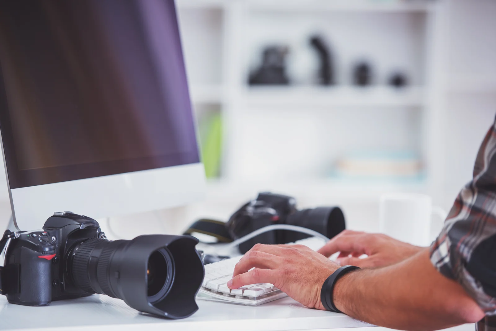 Fotograf pri počítači a monitore počas spracovania fotografií