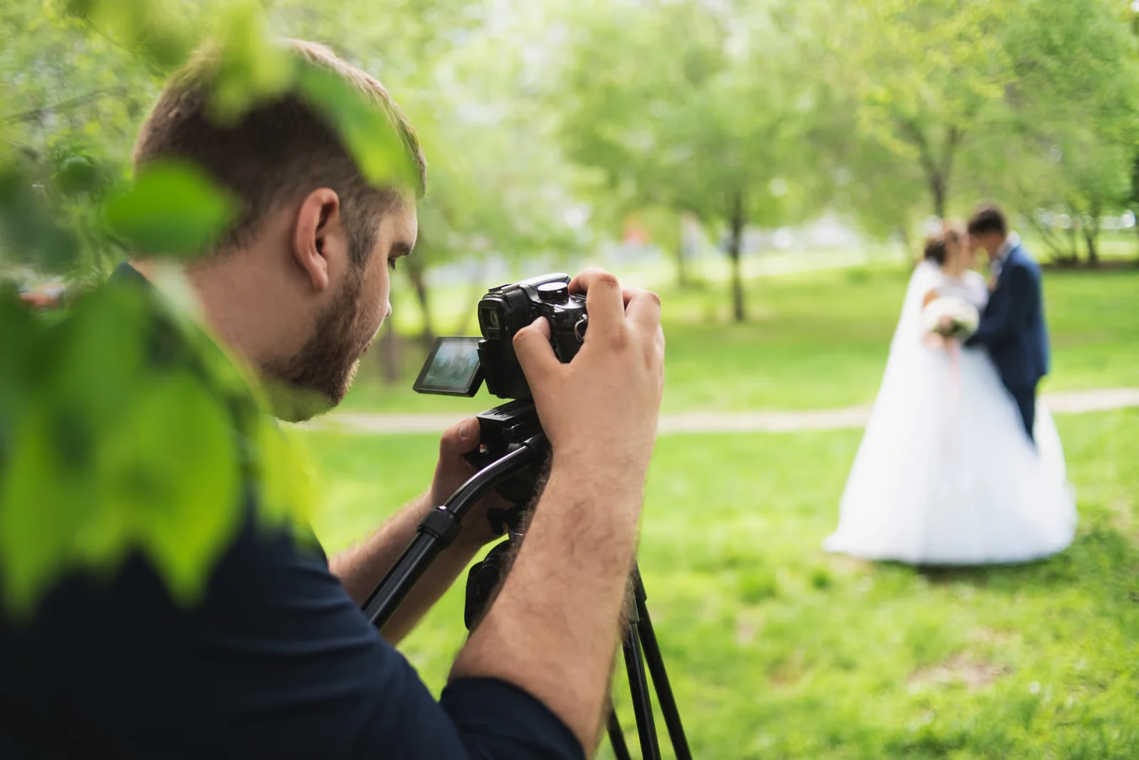 Svadobný fotograf fotí pár v zelenom parku