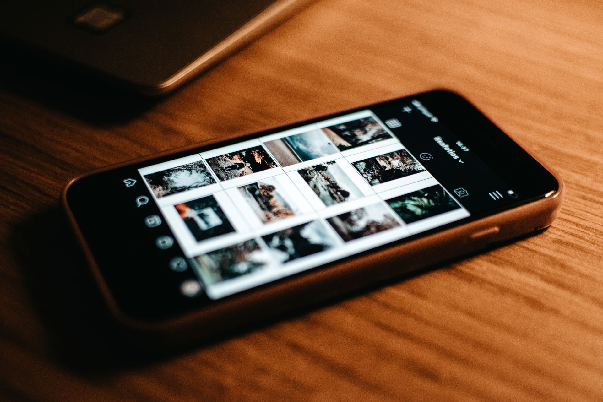 Mobilný telefón s fotografiami na displeji položený na drevenom stole