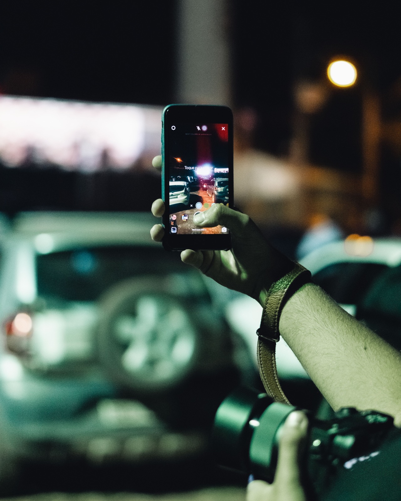 Človek zachytáva nočnú ulicu fotoaparátom staršieho mobilu; ilustračný záber, nie iPhone 17 Pro