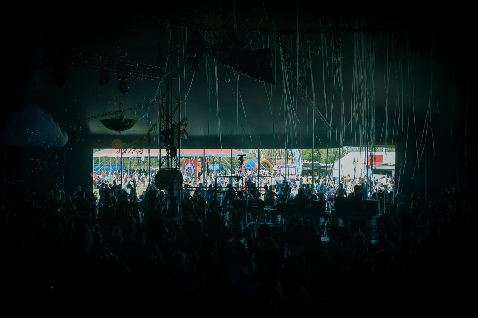 Publikum v tmavom festivalovom stane s výhľadom na svetlý vonkajší areál