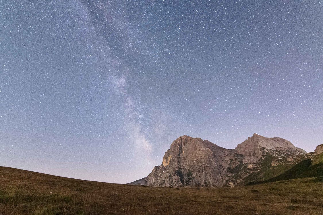 Mliečna dráha na hviezdnej oblohe nad siluetami horských štítov
